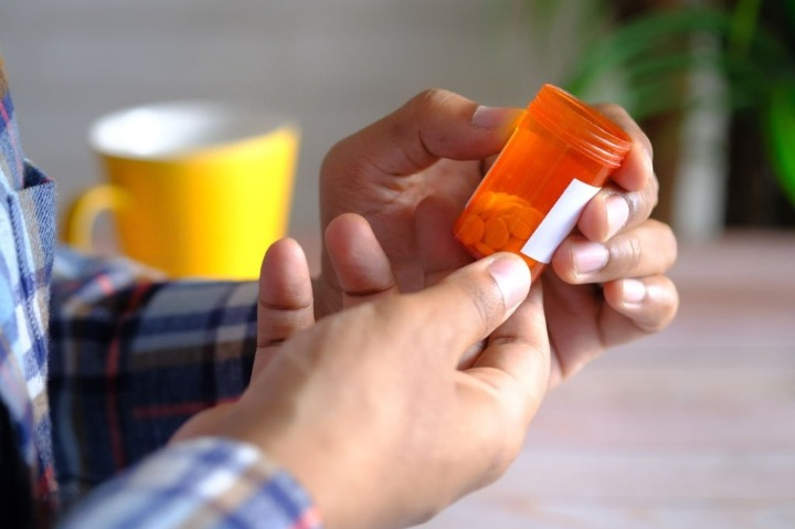 Sick man holding a medicine pill container and thinking about drug addiction treatment